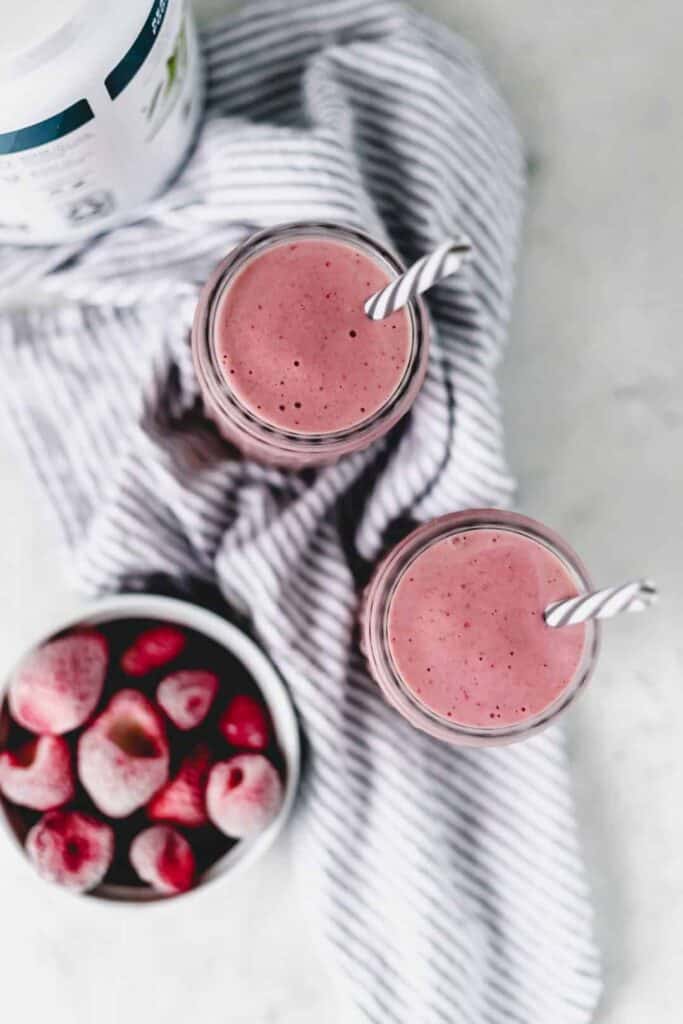 overhead view of strawberry smoothie with bowl of frozen strawberries