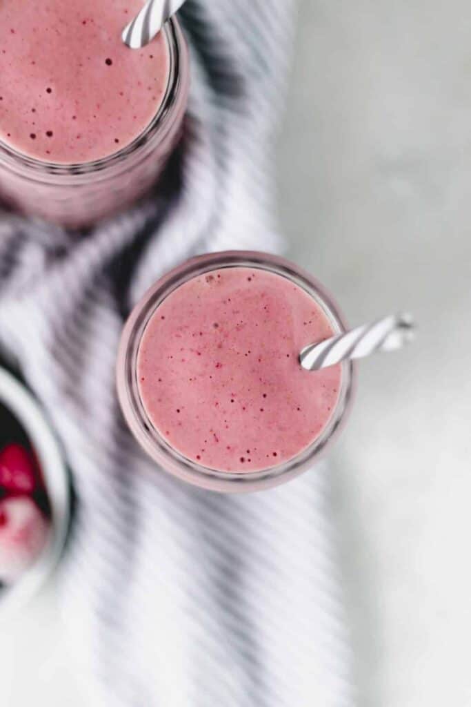 overhead view strawberry smoothie in glass with straw