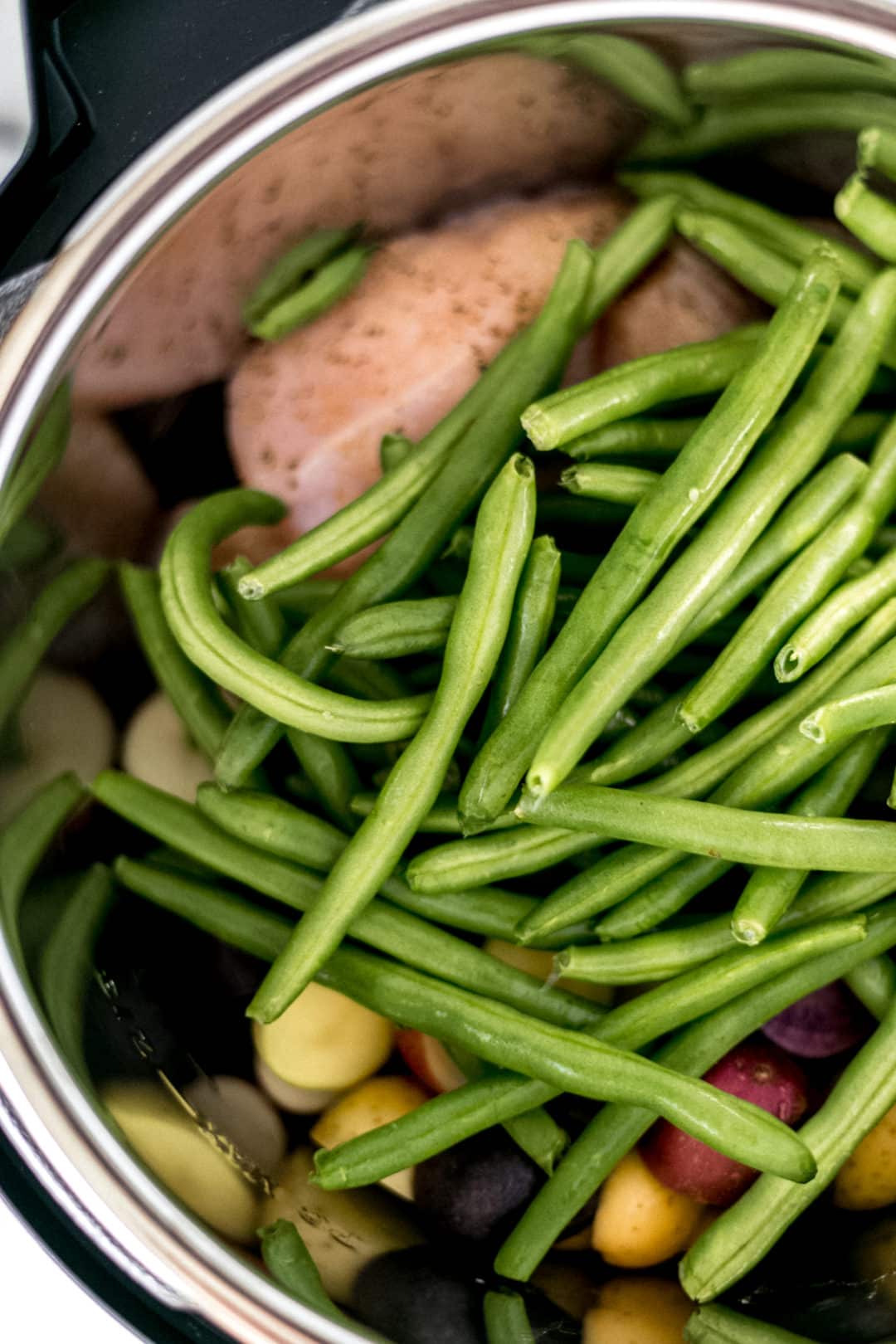 green beans on top of chicken and potatoes in an instant pot