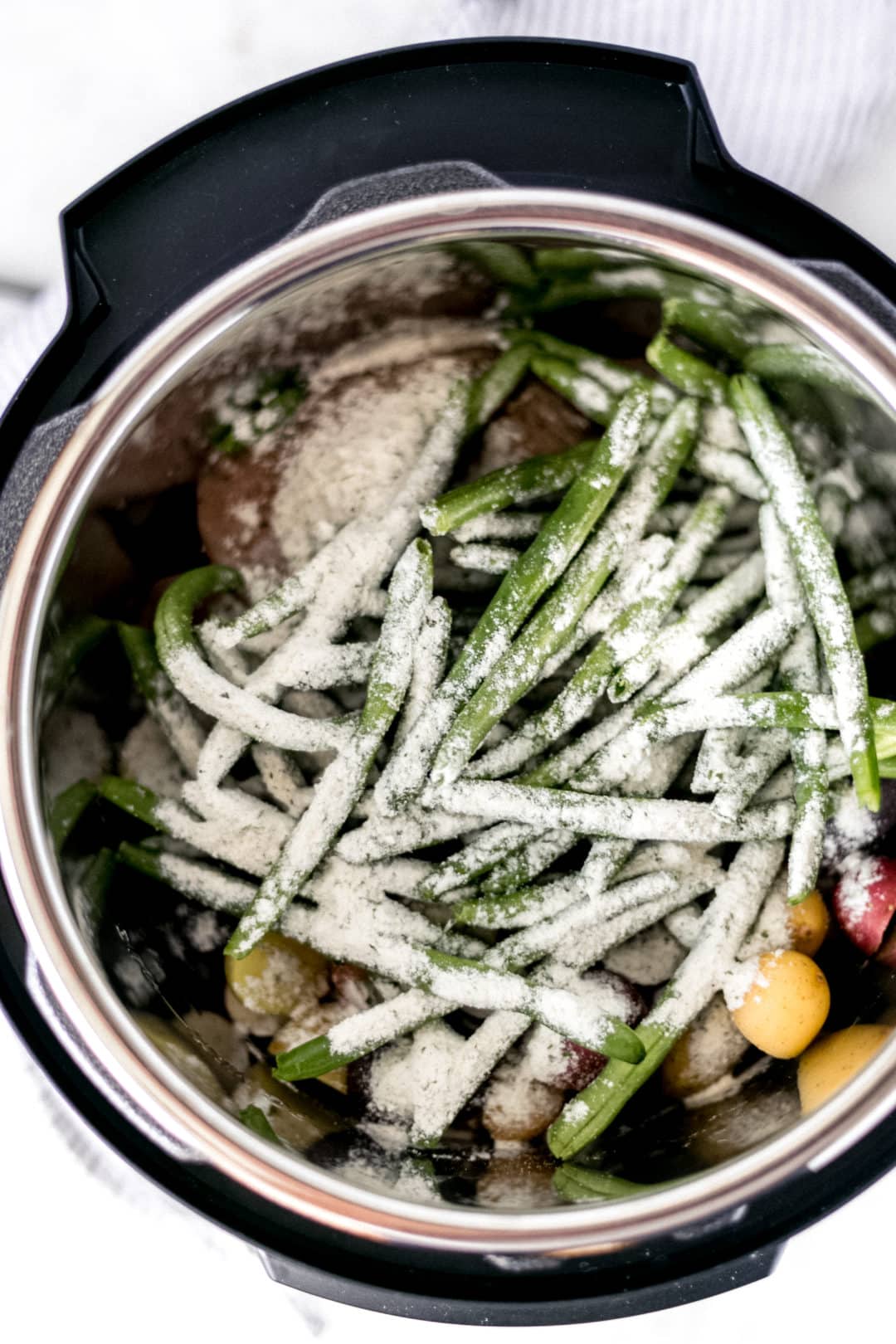 ranch seasoning mix over chicken and potatoes with green beans in a pressure cooker