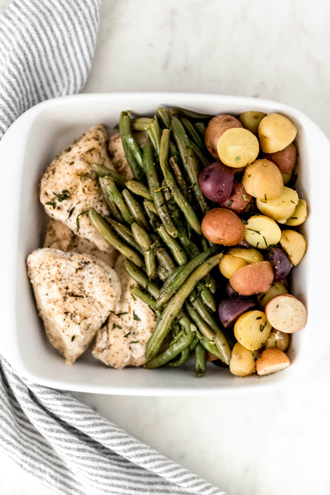 white platter with chicken, potatoes, and green beans
