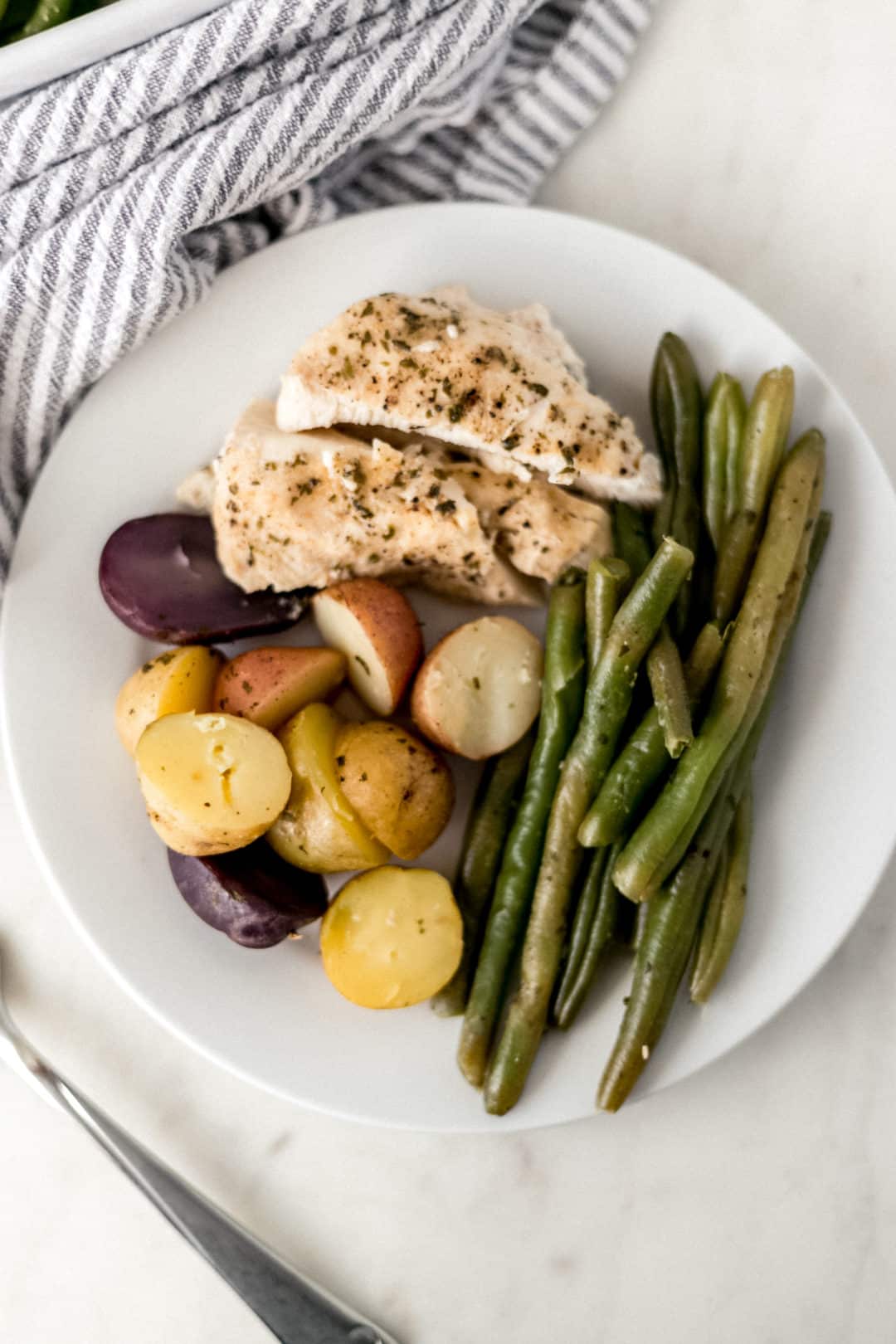white plate with chicken potatoes and green beans