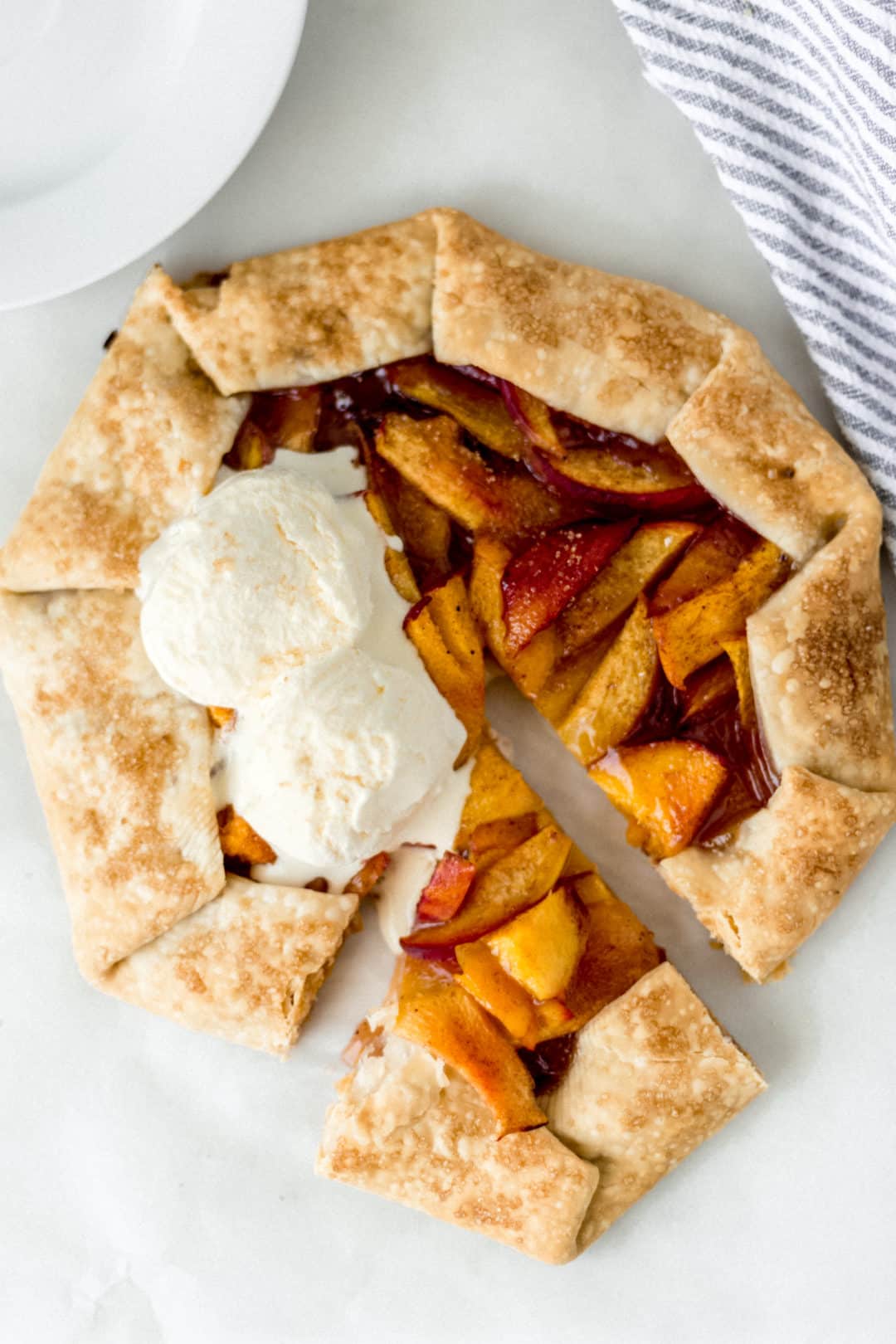 overhead view of peach galette topped with two scoops of vanilla ice cream 