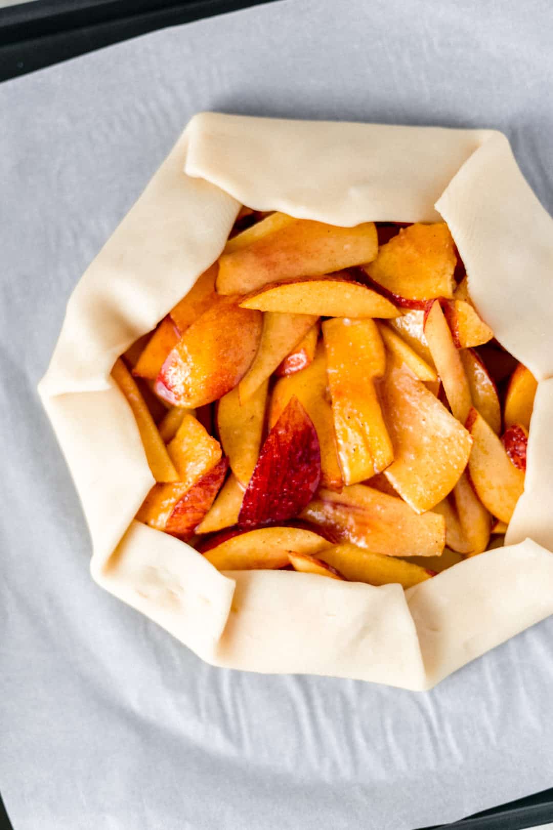 pie crust folded over peach mixture for galette