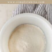 Overhead view of flour in white bowl on pin with text overlay.
