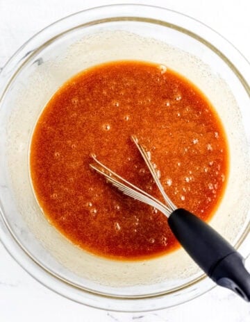 Wet ingredients combined in glass mixing bowl with whisk.