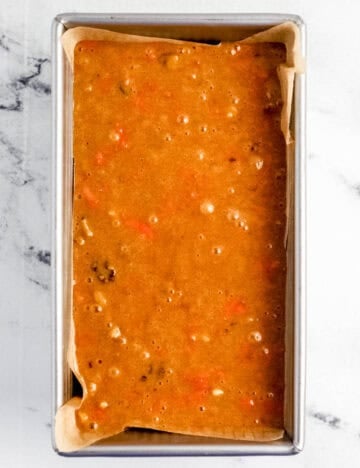 Bread batter added to parchment lined loaf pan.
