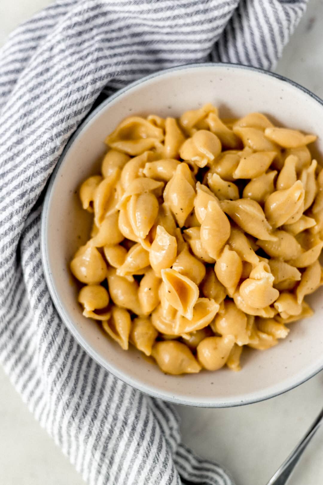 close view of mac and cheese in a bowl by a striped napkin