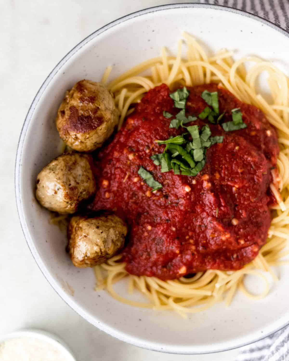 Overhead view of pasta and meatballs in a white bowl.