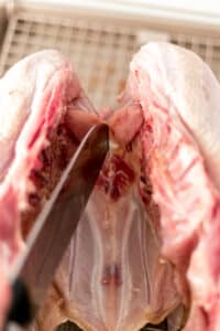 knife cutting into raw turkey