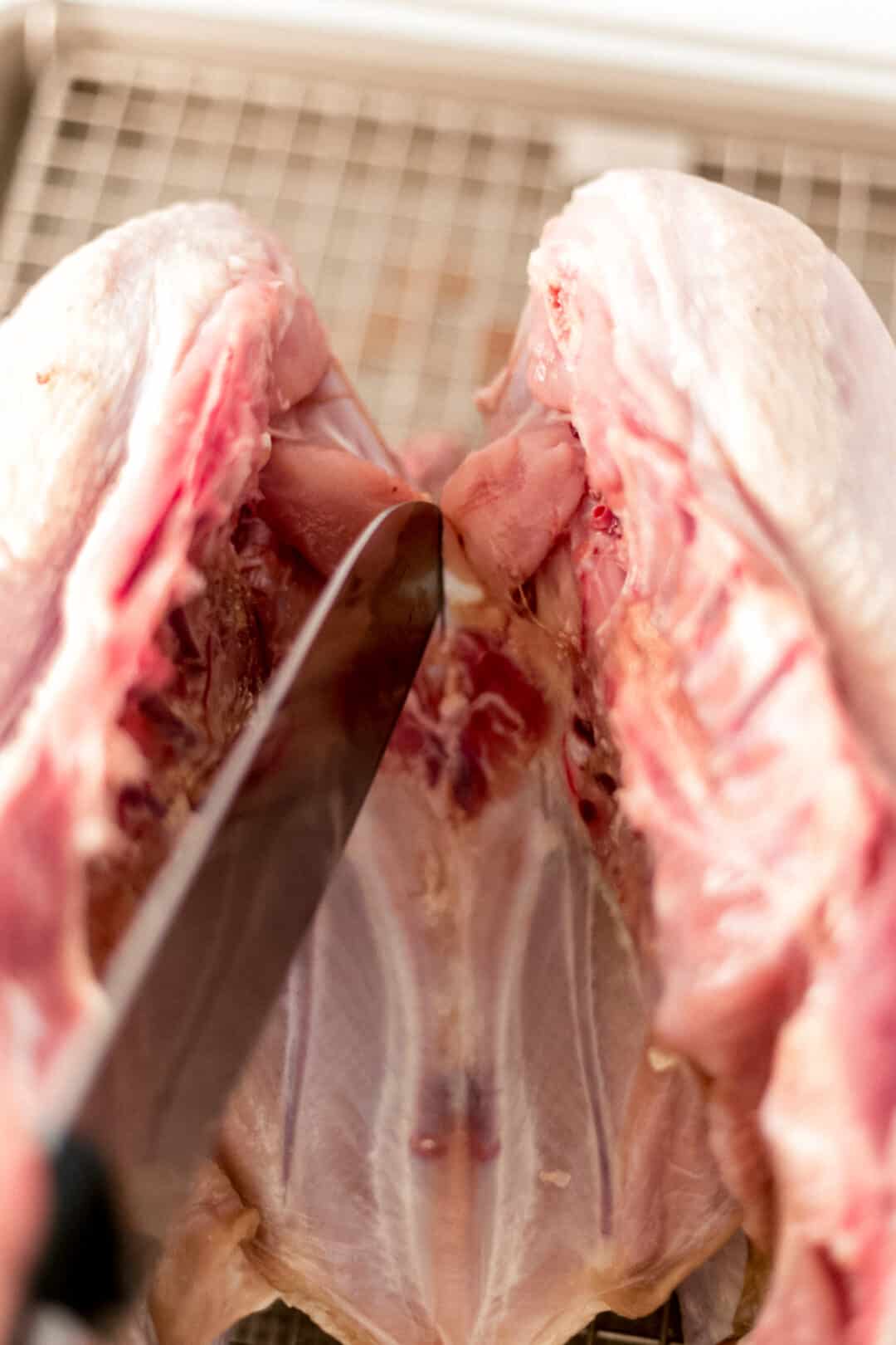 knife cutting into raw turkey 