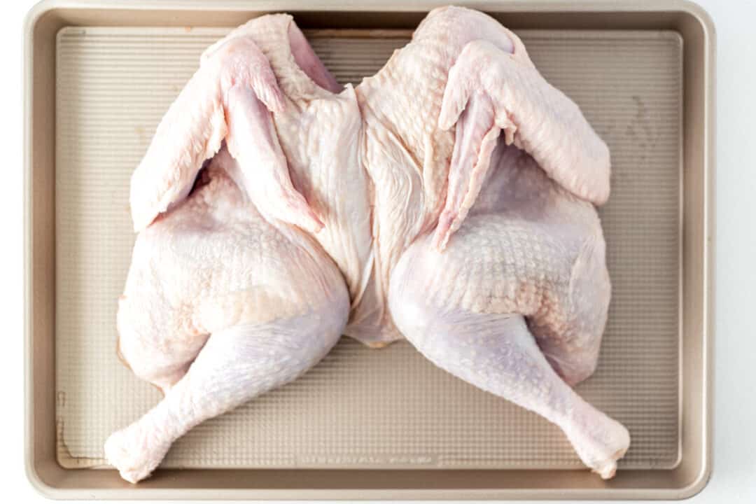 spatchcock raw turkey on large baking sheet 