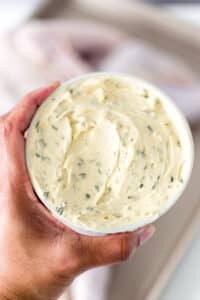 Hand holding bowl of herb butter.