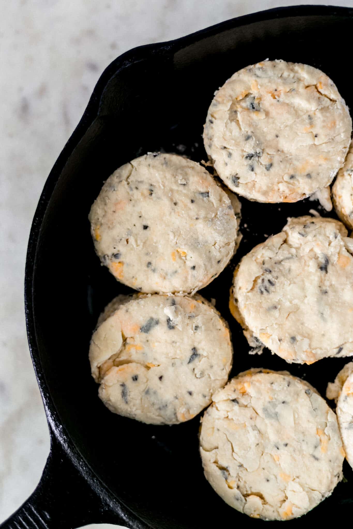 uncooked cheddar and herb biscuits in cast iron skillet