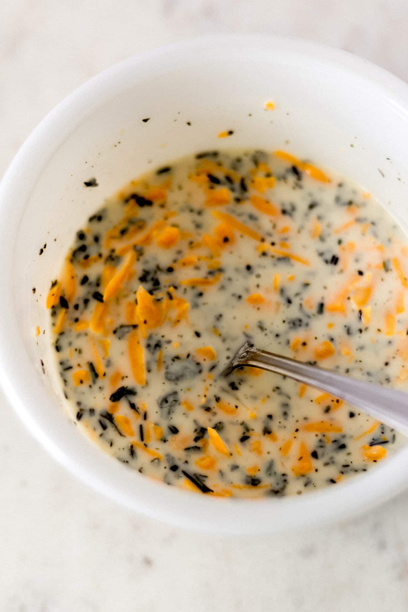 wet ingredients for cheese herb biscuits in small with bowl with fork