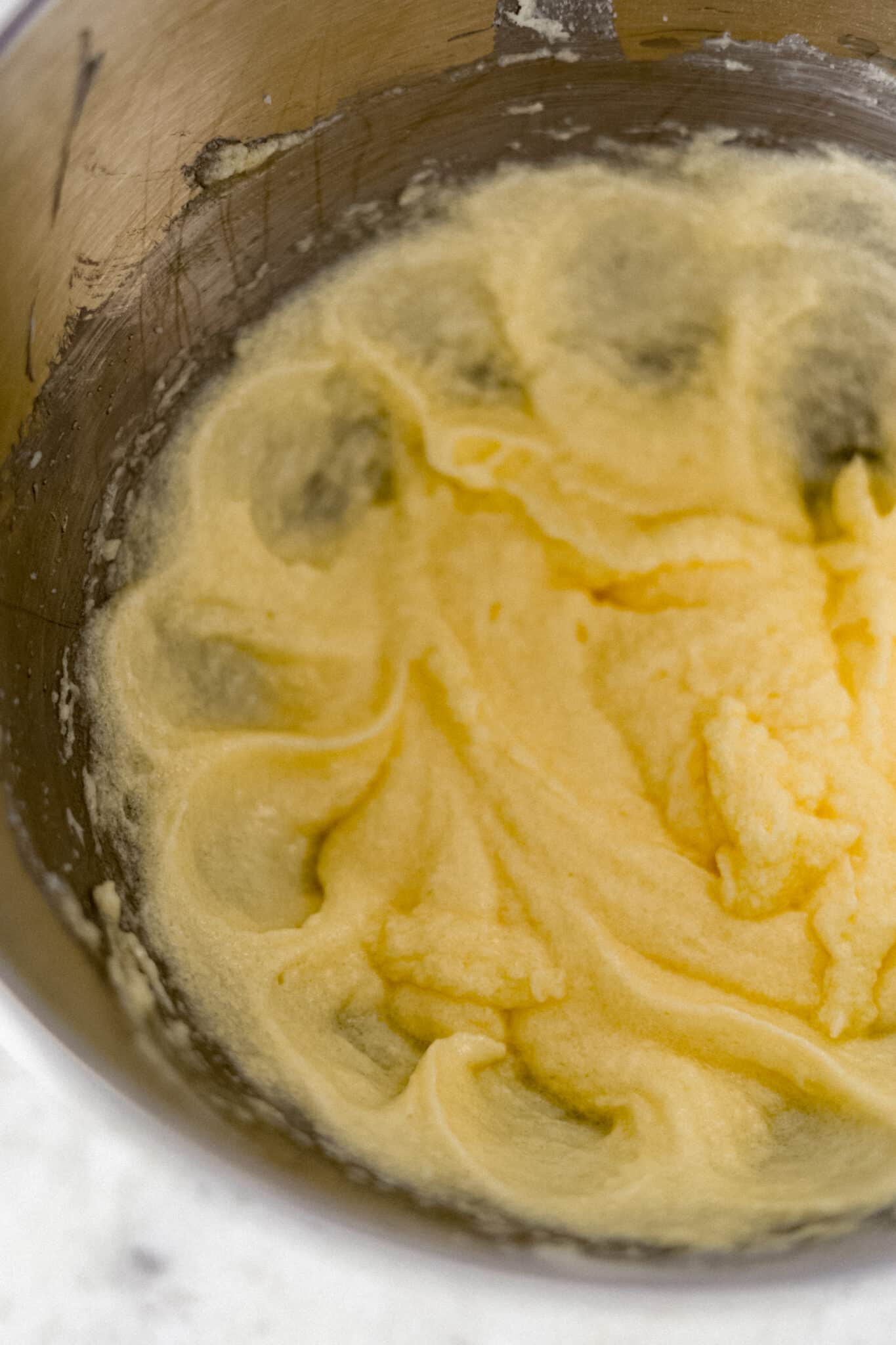butter, sugar, and eggs mixed together in silver mixing bowl