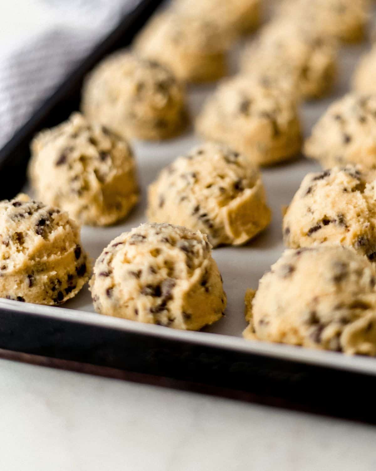 Close up view of cookie dough on parchment lined sheet pan.