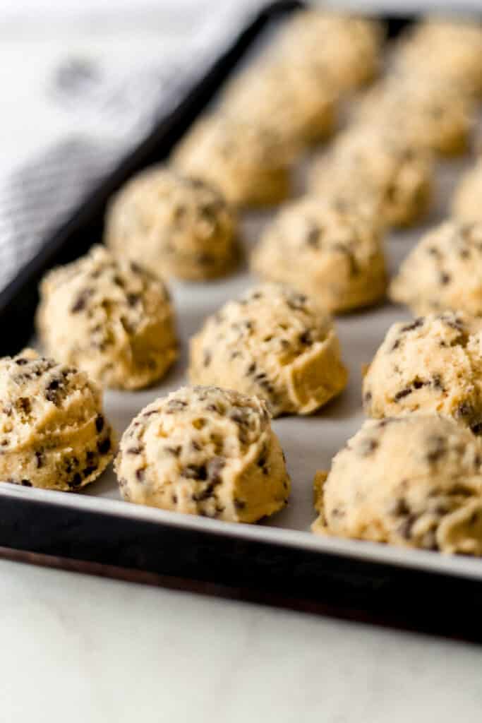 frozen cookie dough balls on a parchment lined baking sheet