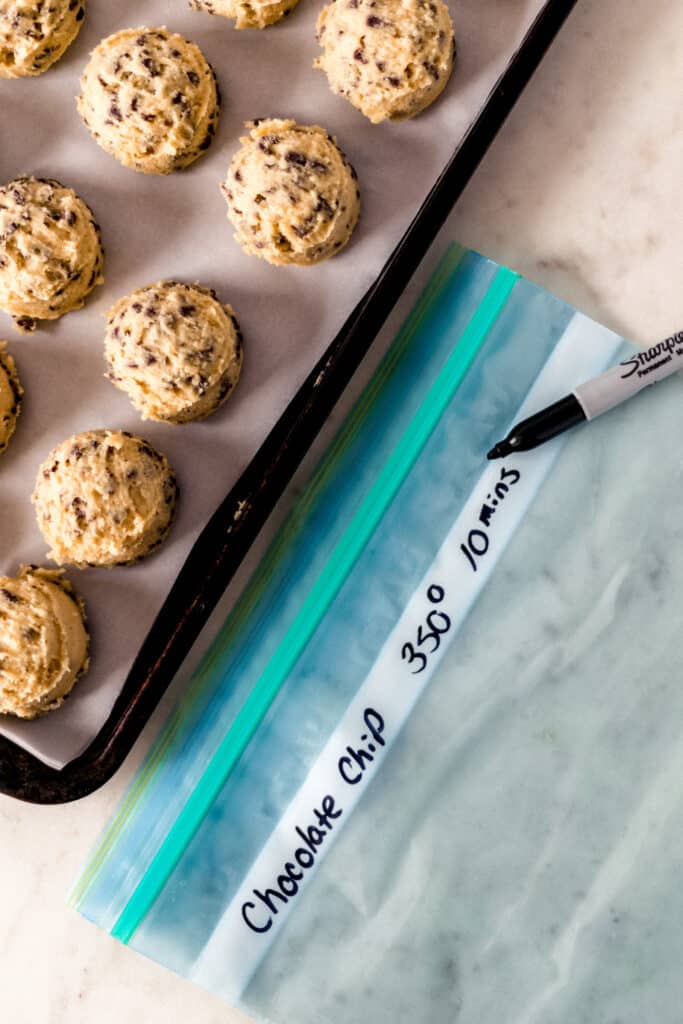 labeled freezer bag next to frozen cookie dough on baking sheet