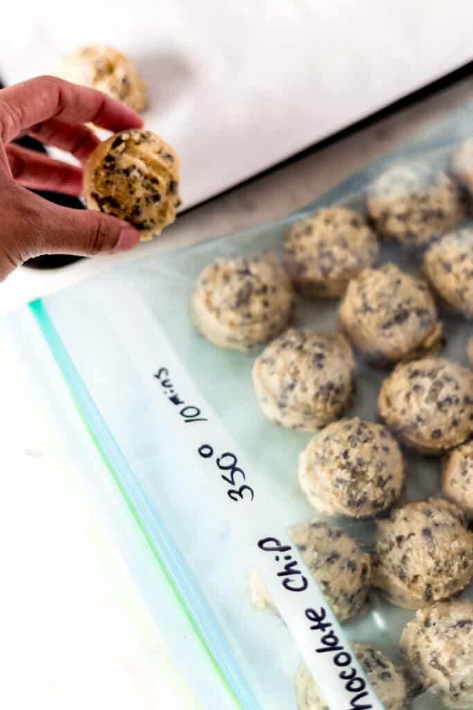 hand placing frozen cookie dough into a labeled freezer bag