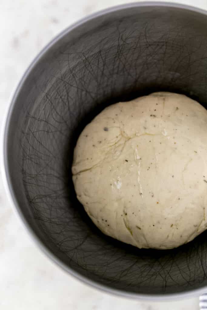 pizza dough covered with olive oil in stand mixer bowl