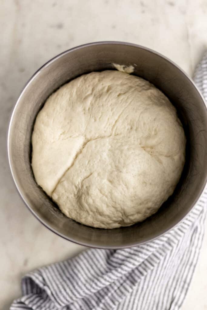 pizza crust in mixer bowl that has doubled in size after rise time.