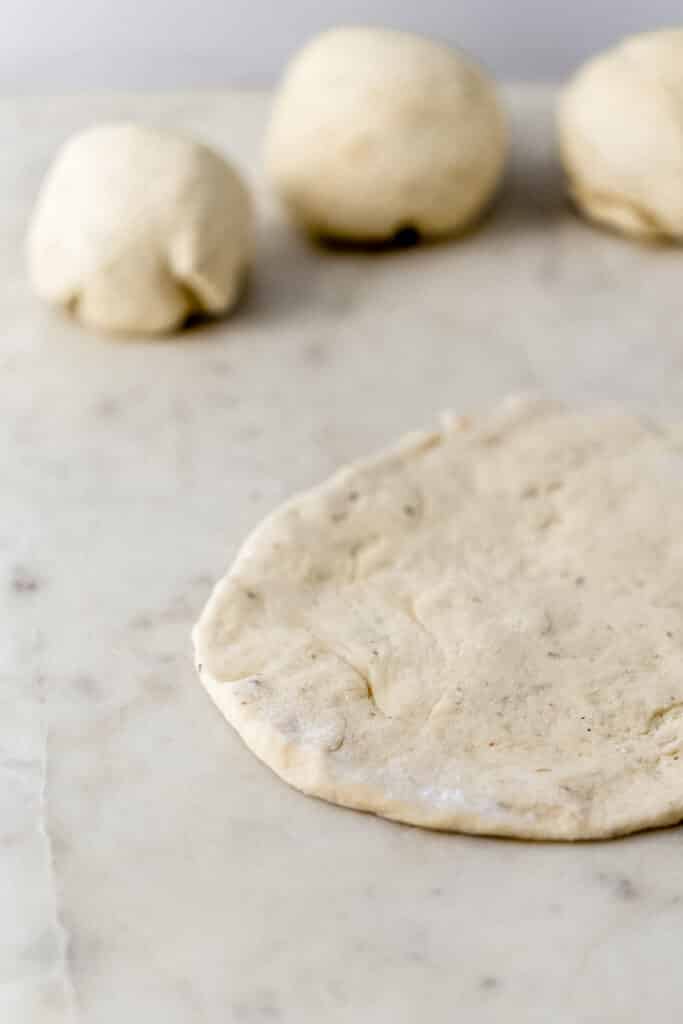 pizza dough divided an rolled out on marble surface 