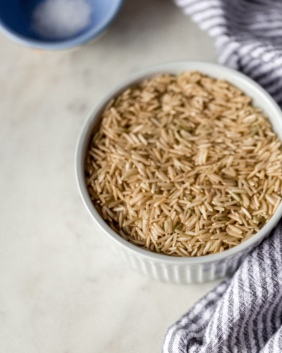 Close up view of bowl of rice and salt by cloth napkin. 