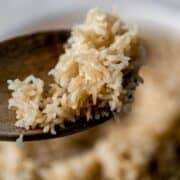 Wooden spoon with rice on it.