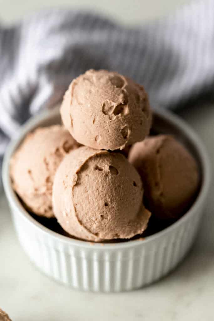 close up side view keto chocolate fat bombs in white bowl