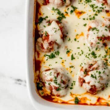 finished meatball casserole topped with chopped parsley in baking dish