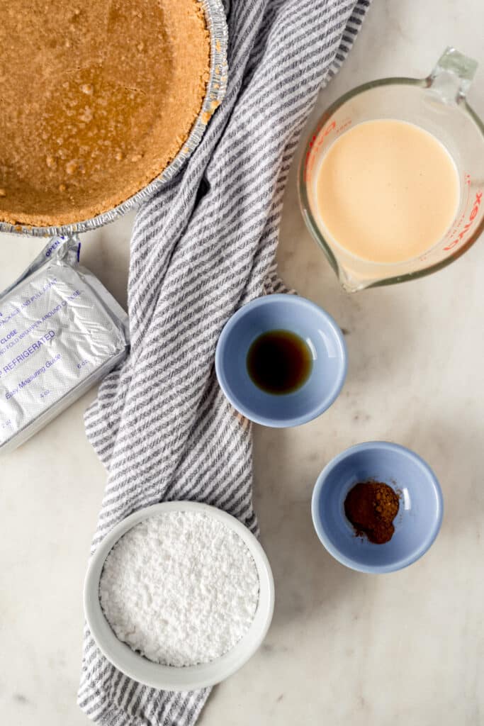 ingredients for no bake eggnog cheesecake in small bowls and containers with napkin