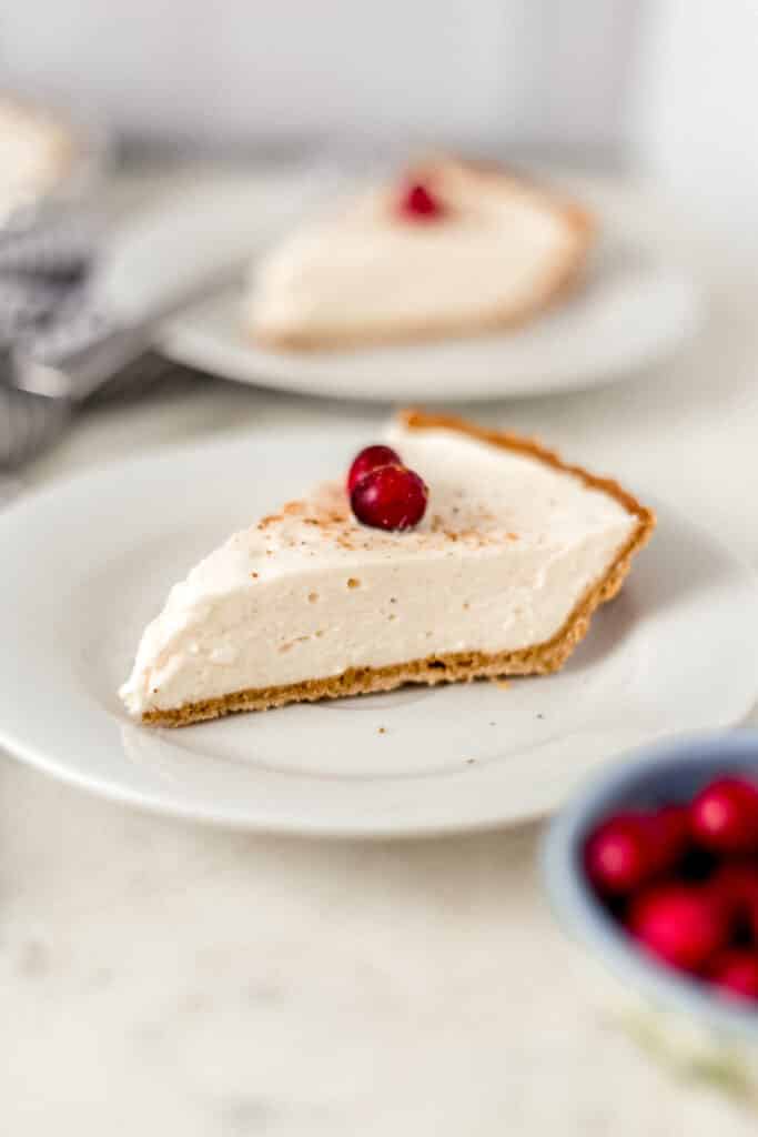 slice of eggnog cheesecake on a white plate with another slice in the background
