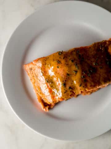 overhead view piece of brown sugar dijon glazed salmon on white plate