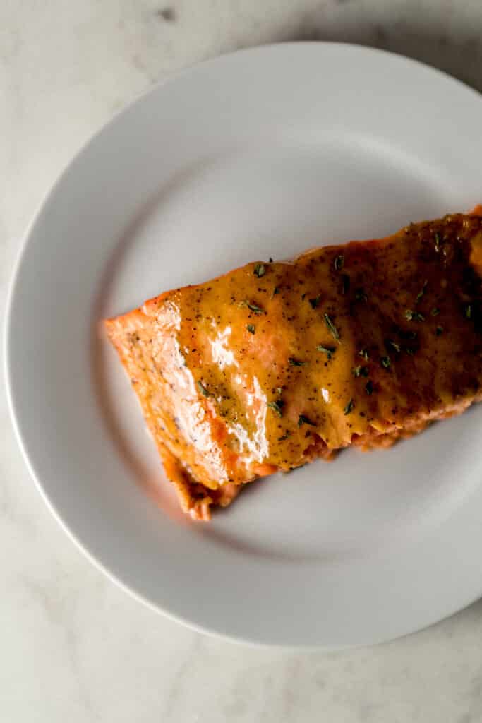 overhead view piece of brown sugar dijon glazed salmon on white plate