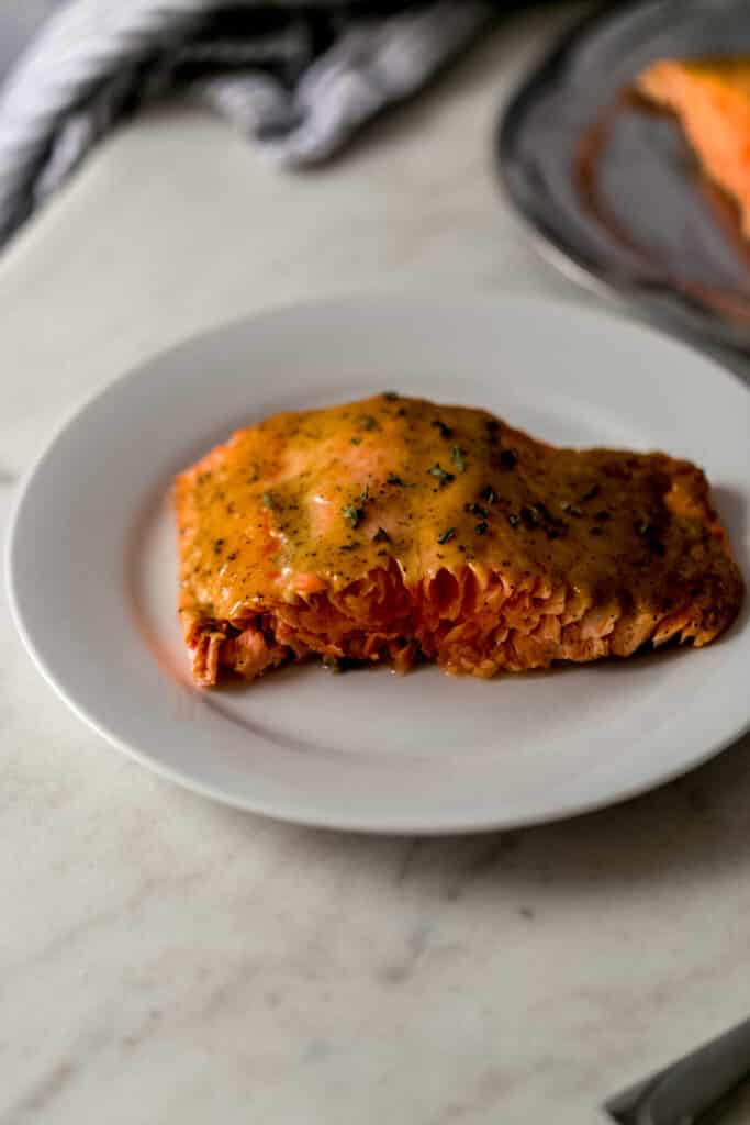 close up side view brown sugar dijon glazed salmon on white plate