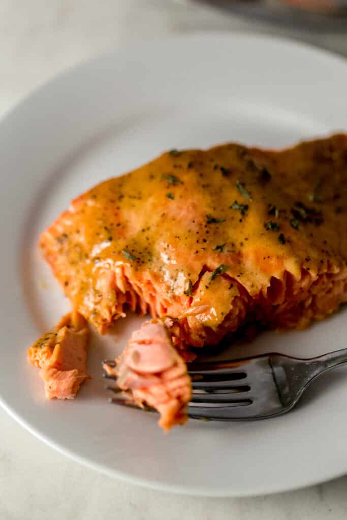 close up view glazed salmon on white plate with fork 