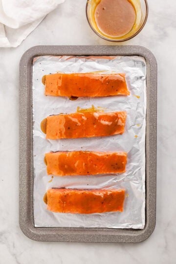 Salmon topped with glaze on foiled lined sheet pan.