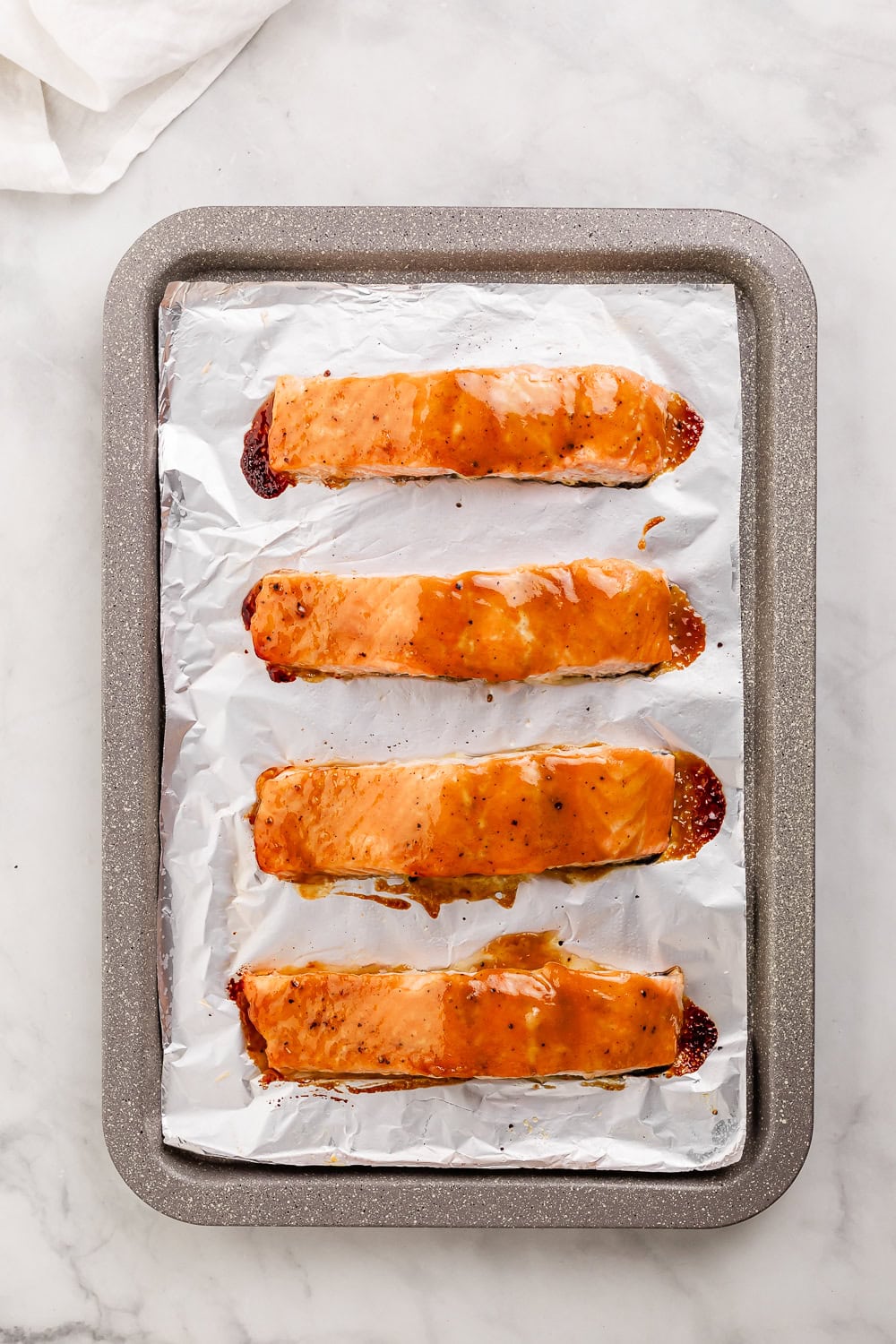 Overhead view of baked salmon on foil lined baking sheet.