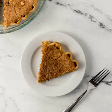 slice of pie on white plate beside a fork and the rest of the pie
