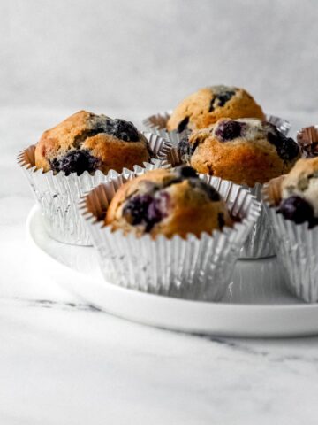 Close up side view of muffins on white plate.