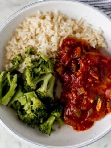 Overhead view of white bowl of pork chops, rice, and broccoli.