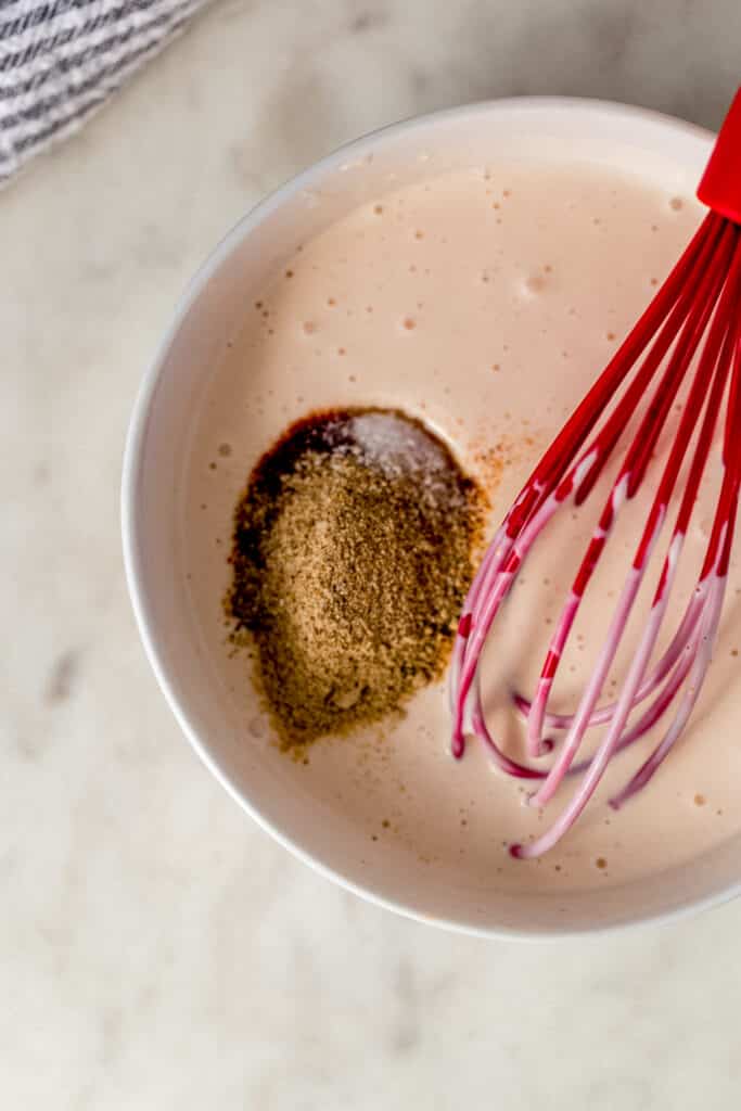 seasoning added to white bowl with red whisk to make yum yum sauce