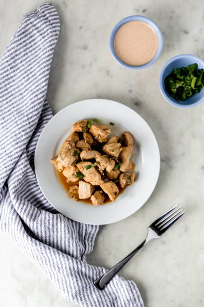 hibachi chicken on white plate next to fork and napkin