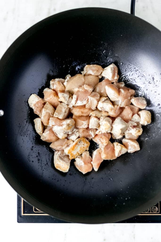 chicken added to heated wok with oil 