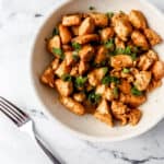 Overhead view of finished hibachi chicken in a white bowl by a fork.