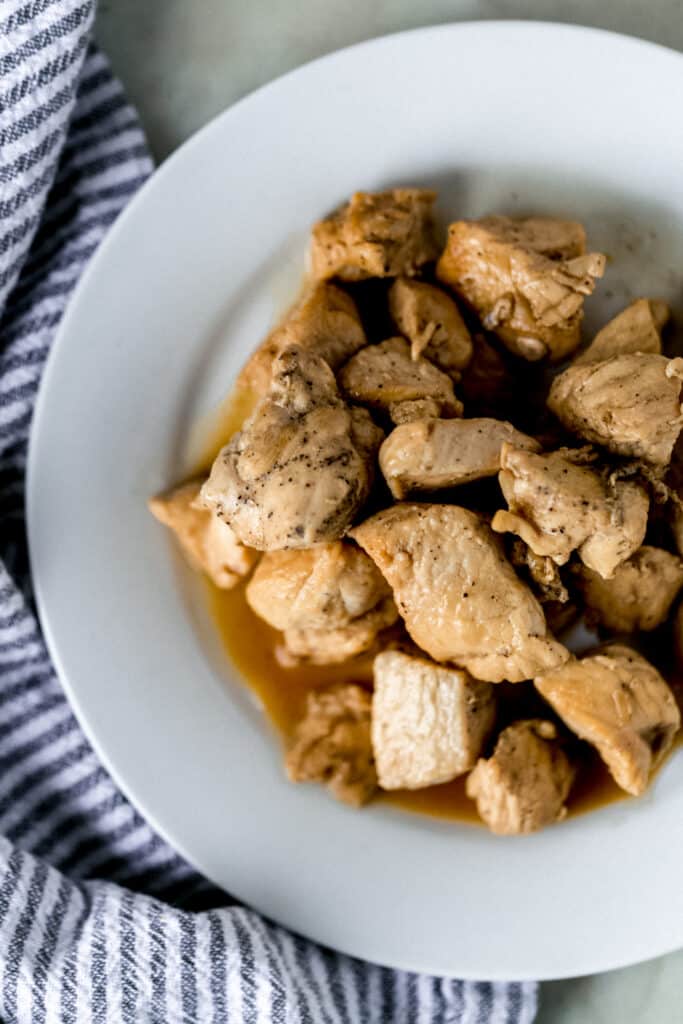 hibachi chicken on white plate next to cloth stripped napkin
