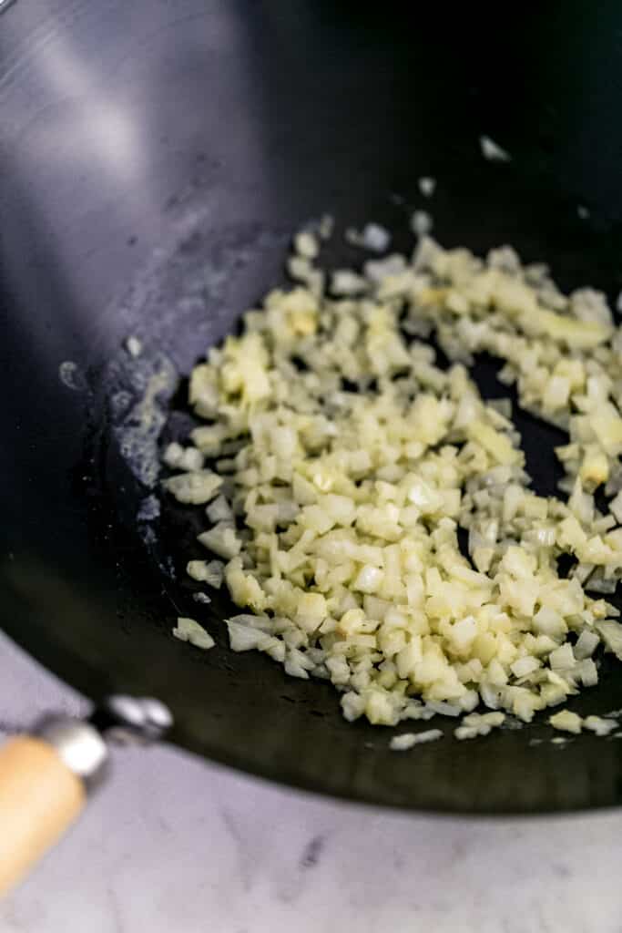 chopped onion cooking in butter in a black wok