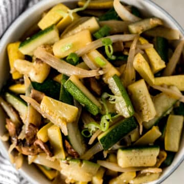 cooked hibachi vegetables in a big white bowl beside a napkin