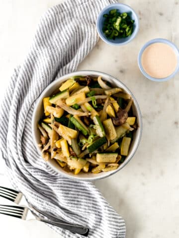 hibachi vegetables in a large white bowl with napkin and forks